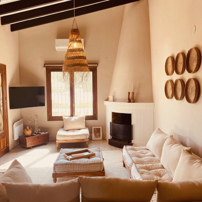 Casa Orange Moraira: metamorfose van mediterraanse villa, verbouwd met behoud van originele terrazzo vloertegels uit 1974, open haard en hoge plafonds. Ingericht met lokaal vervaardigde materialen uit de regio. Wat een sfeervolle woonkamer is het geworden!